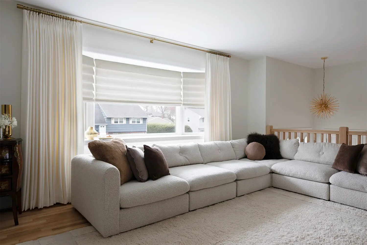 Living room with cream drapes, roman shade and a sectional sofa