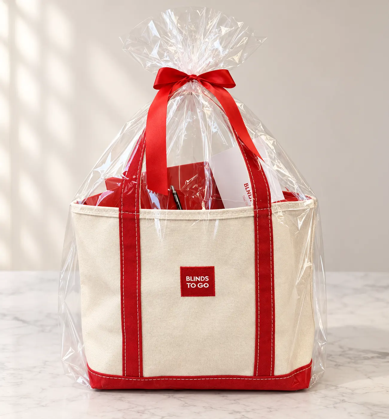 Canvas tote bag with red trim wrapped in cellophane and a red ribbon