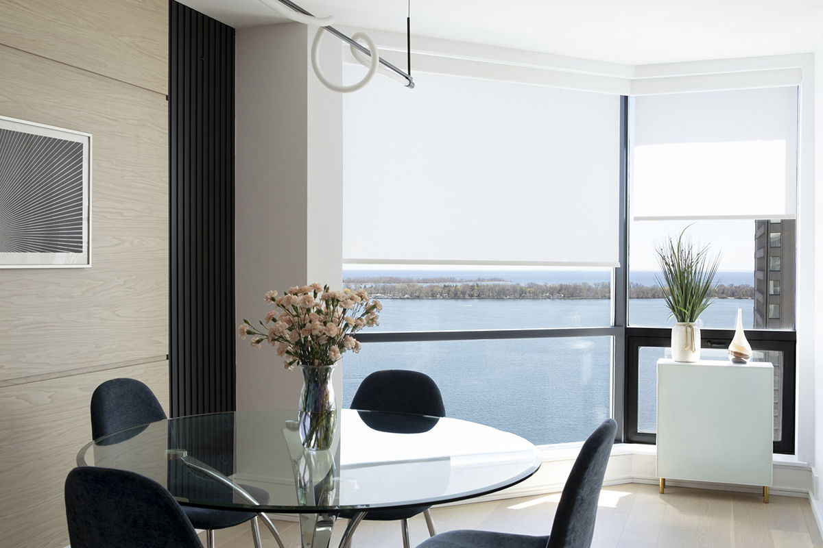 Floor-to-ceiling windows are covered with light-filtering roller shades in white in a modern apartment look out over the water Floor-to-ceiling windows are covered with light-filtering roller shades in white in a modern apartment look out over the water