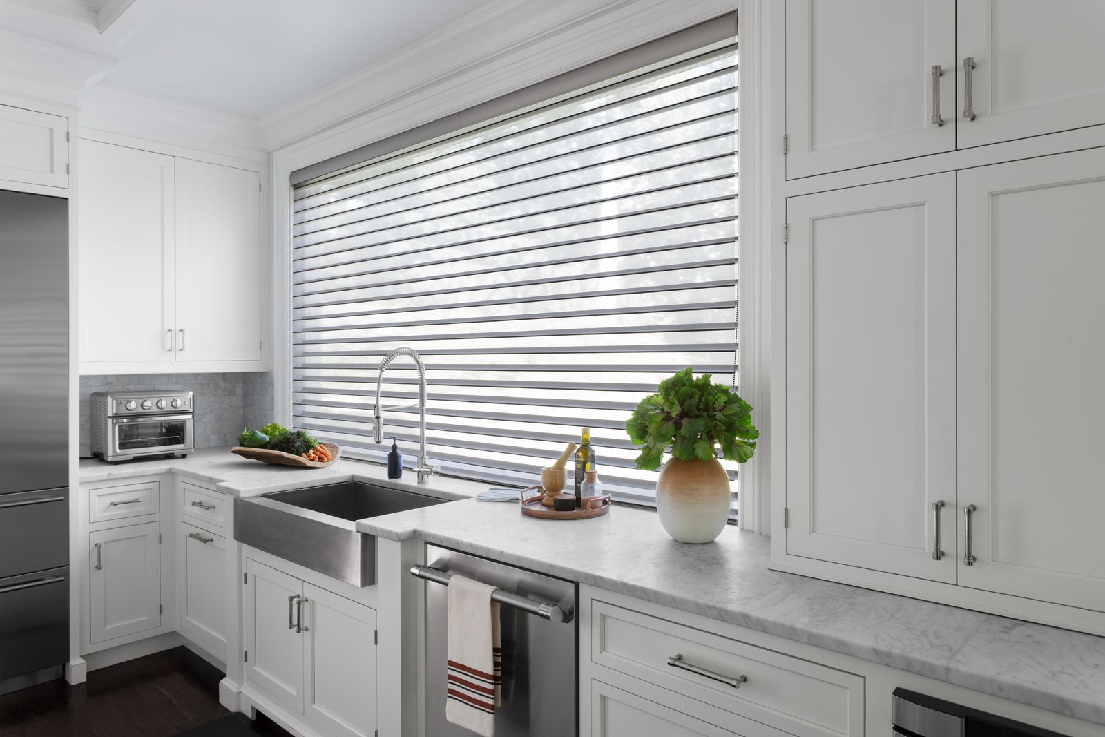 A Serenity sheer shade in grey covers a large window in a spacious kitchen A Serenity sheer shade in grey covers a large window in a spacious kitchen