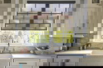 Solar shades cover a large window behind the sink in a modern farmhouse kitchen.