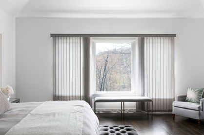 Fabric vertical blind in light grey in an airy bedroom