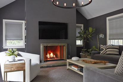 A cozy dark grey living room has three windows covered with real wood blinds in a grey hue A cozy dark grey living room has three windows covered with real wood blinds in a grey hue